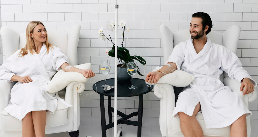 smiling couple at a spa in robes getting IV Therapy treatment